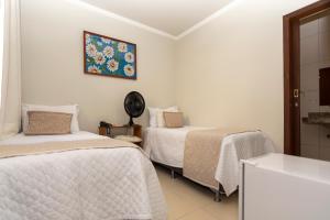 1 dormitorio con 2 camas y reloj en la pared en POUSADA CAPIM LIMÃO, en Diamantina