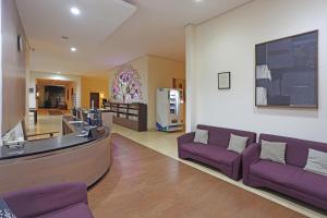 a lobby with purple couches and a bar in a building at ARCS House Pakubuwono by Jambuluwuk in Jakarta