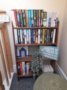 a book shelf filled with books next to a plant at Seaglass Cottage - Redcar in Redcar