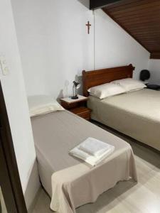 2 camas en una habitación con una cruz en la cama en Casa Leicht - Quarto Família, en Blumenau
