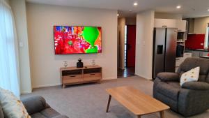 uma sala de estar com dois sofás e uma televisão na parede em El Beracca Retreat - 3 bedroom home away from home em Palmerston North