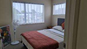 um quarto com uma cama, uma janela e uma ventoinha em El Beracca Retreat - 3 bedroom home away from home em Palmerston North