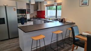 a kitchen with a large counter with stools in it at El Beracca Retreat - A home away from home in Palmerston North