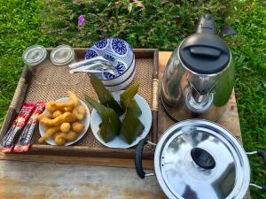 a tray with a tea pot and a plate of food at บ้านแม่อุทัยธานี Baanmae Uthaithani in Uthai Thani