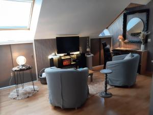 a living room with two chairs and a tv at Reve gourmand in Beauraing