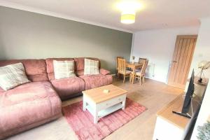 a living room with a couch and a table at Comfortable Norfolk Bungalow in Dersingham