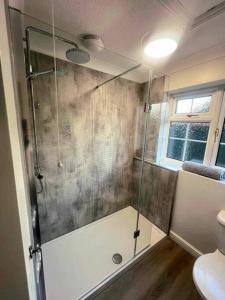 a bathroom with a shower with a glass door at Comfortable Norfolk Bungalow in Dersingham