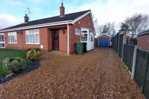 a brick house with a fence and a driveway at Comfortable Norfolk Bungalow in Dersingham