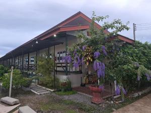 Una casa con flores púrpuras a un lado. en Sailom Resort​, en Chom Thong