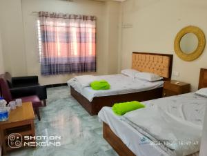 een kamer met 2 bedden, een stoel en een spiegel bij Coral lagoon resort in Jaliapāra
