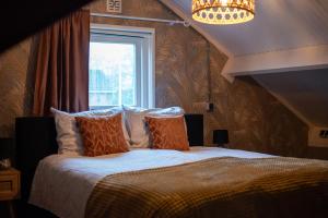 een bed met oranje kussens in een kamer met een raam bij Sfeervol Appartement Het Knooppunt in Nuis