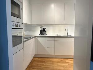 a white kitchen with white cabinets and a sink at Newly produced and bright apartment close to metro in Solna