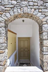 un arco de piedra con una puerta en un pasillo en Raffar luxury houses Psarou en Platis Yialos Mykonos