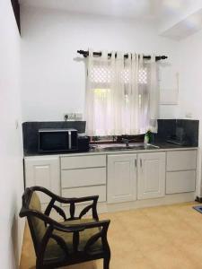 a kitchen with a black chair and a microwave at Comfortable and serene cottage surrounded with palms and tamarind tree in Rajagiriya