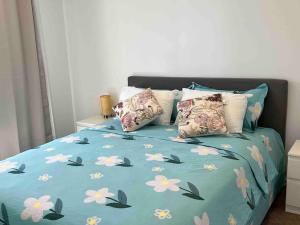 a bed with a blue comforter with flowers on it at Gungahlin Center-1 Bedroom New Stylish Unit in Harrison