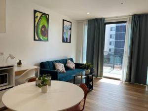 een woonkamer met een blauwe bank en een tafel bij Gungahlin Center-1 Bedroom New Stylish Unit in Harrison
