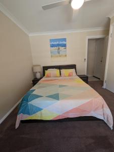 1 dormitorio con 1 cama con una manta colorida en Luxury oasis resort Pet friendly apartment with private pool and spa en Port Macquarie