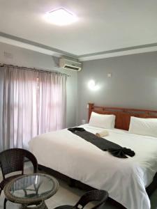 a bedroom with a large white bed and a table at Global Guest House in Kasane