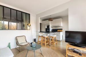 een woonkamer met een televisie en een tafel en stoelen bij Le Jules de Toulouse in Toulouse