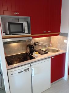 cocina con armarios rojos, fregadero y microondas en Vue Golf dans Résidence Nature "SYMPALAPPART", en Moliets-et-Maa