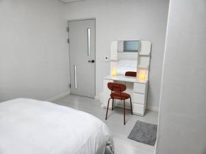 a white bedroom with a bed and a desk with a mirror at Suwon station City House in Suwon