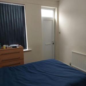 1 dormitorio con cama, ventana y vestidor en Home away from home, en Leicester