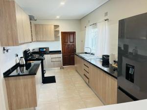 Una cocina con gabinetes de madera y un refrigerador negro. en Elisheva apartment, en Ndola