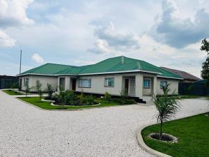 una casa con techo verde en una entrada de grava en Elisheva apartment, en Ndola