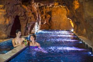 Ein Mann und eine Frau in einem Pool in einer Höhle in der Unterkunft Bambara Hotel Premium in Felsőtárkány