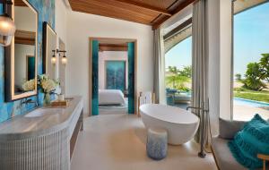 a bathroom with a tub and a sink and a bedroom at The St. Regis Red Sea Resort in Ḩanak