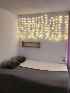 een slaapkamer met een bed met verlichting aan de muur bij Appartement cosy et chaleureux in Morez