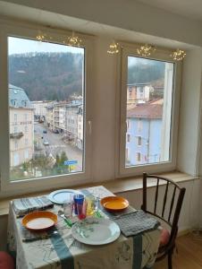 a dining room table with two chairs and two windows at Appartement cosy et chaleureux in Morez