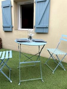 einen Tisch und zwei Stühle sowie ein Fenster mit blauen Rollläden in der Unterkunft VILLA GABY ~ Jardinet ~ hyper-centre in Pau