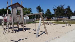 een speeltuin met een schommel in het zand bij Cottage chalet gîte l'Edune résidence de vacances location in Jullouville-les-Pins