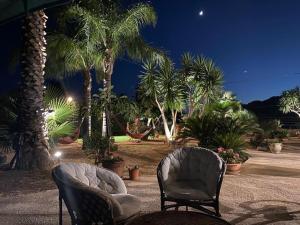 two chairs and palm trees in a park at night at Casamare San Giorgio 2 in Sciacca