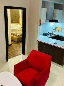 a red chair in a kitchen with a bedroom at Cherry On Top-Luxe Living in Islamabad's Skyline Elysium in Islamabad