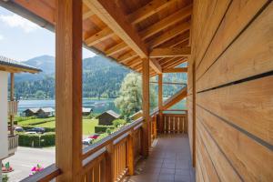a wooden house with a balcony with a view of a lake at Ferienhof Neusacher Moser in Weissensee