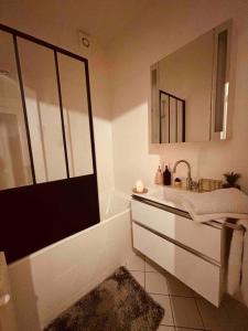 bagno con vasca, lavandino e specchio di élégance à Neuilly : 5 min des Champs Elysées a Neuilly-sur-Seine