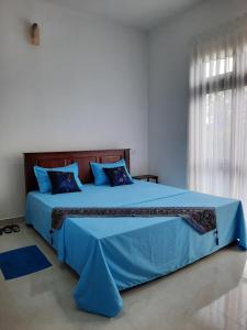 ein Schlafzimmer mit einem großen Bett mit blauer Bettwäsche und einem Fenster in der Unterkunft "The Anchorage" of Field View in Pannipitiya