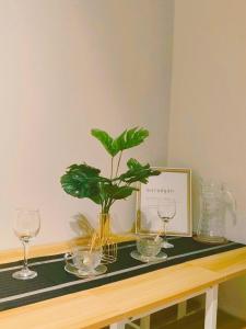 a table with two wine glasses and a plant on it at Grass Residences by Team A in Manila