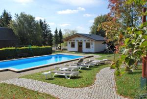 uma piscina com espreguiçadeiras ao lado de uma casa em Hotel Alpenhof em Markneukirchen