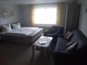 Sala de estar con sofá, cama y mesa en Pension Arndt UG en Wangerland