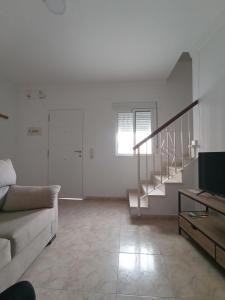 uma sala de estar branca com um sofá e escadas em El 20 em Barbate