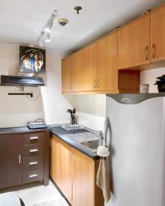- une cuisine avec des placards en bois et un réfrigérateur blanc dans l'établissement Affordable Staycation Airbnb BGC, à Manille