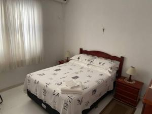 een slaapkamer met een bed met witte lakens en een raam bij Apto Térreo in Blumenau