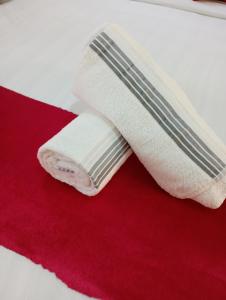 a roll of white towels sitting on a red blanket at Cozy furnished studio in Nairobi