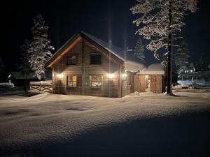een houten hut met 's nachts verlichting in de sneeuw bij Chillouthouse Idre in Idre