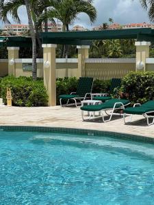 a swimming pool with two lawn chairs and a table at Carey Beach Villa in Humacao