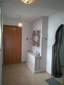 Habitación con puerta, lavabo y espejo. en Ático Dúplex con vistas en Murcia