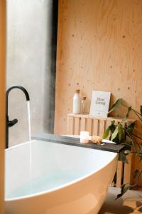 y baño con bañera y pared de madera. en Vague Luxurious Tiny House Luxe Wellness, Spa Bad,Beamer, Veluwe, en Nunspeet